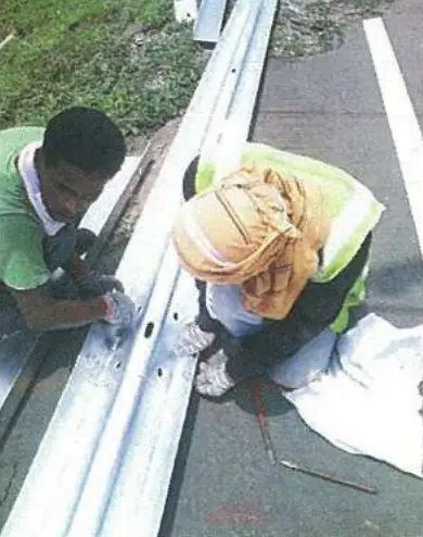 Workers bolting a W-beam guardrail section
